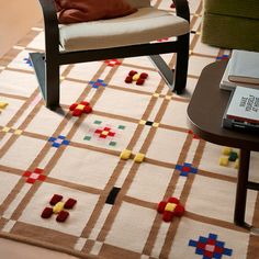 a chair and table in a room with a rug on the floor that looks like an area rug