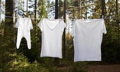 two white shirts hanging on a clothes line in the woods