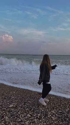 a woman standing on top of a beach next to the ocean