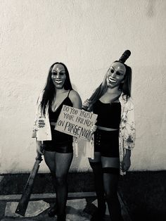 two women dressed in costumes and holding signs