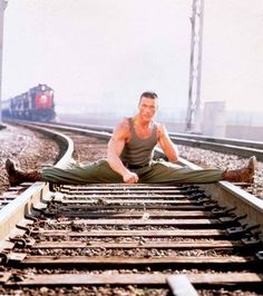 a man is sitting on train tracks with his legs spread out in front of him