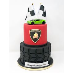 a red and black cake with a green car on it's top, in front of a white background