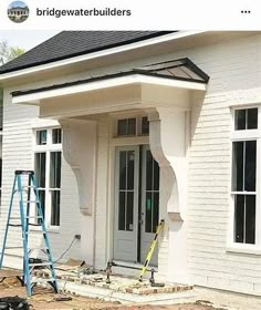 a house being built with white paint and black shingles on the front door, windows and trim