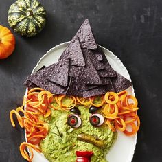 a plate topped with guacamole and chips on top of it next to an orange pumpkin