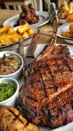 a large steak is on a plate with other foods and condiments around it