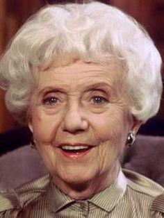 an older woman sitting in a chair with her eyes wide open and smiling at the camera