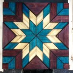 a wooden wall hanging with blue, brown and yellow designs