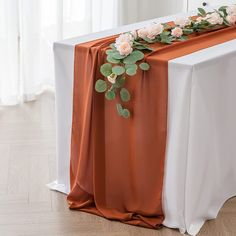 an orange and white table runner with flowers on it