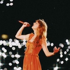 a woman in an orange dress singing into a microphone