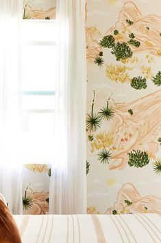 a bed sitting under a window next to a wallpaper covered in green and yellow plants