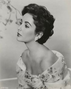 an old black and white photo of a woman with short hair wearing a flowered dress