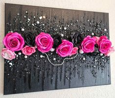 pink and black roses are displayed on a wall