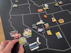 a person pointing at a map with pins and magnets attached to it on a table