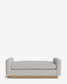 a white couch sitting on top of a wooden frame in front of a gray wall