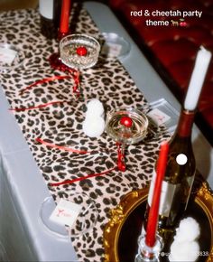 the table is set with red and cheetah party decorations, candles, and wine bottles