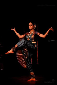 a woman is dancing in the dark with her arms out and legs spread wide open