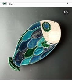 a fish shaped dish with green and blue designs on it