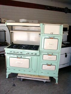 an old fashioned green stove and oven in a room with other appliances on the floor