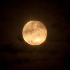 the full moon is seen through clouds at night