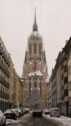 a very tall building with a clock on it's face in the middle of a snowy street