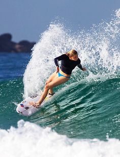 a woman riding a wave on top of a surfboard