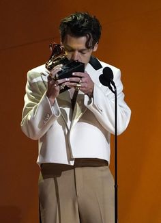 a man in a suit holding an award while standing next to a microphone on stage