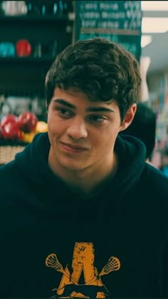 a young man in a black hoodie is looking at the camera