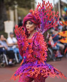 a woman dressed in purple and red is walking down the street