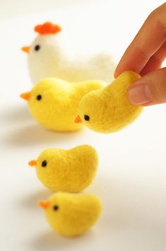 a hand is picking up some tiny yellow chicks from the line in front of them