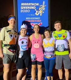 four people in costume standing next to each other at a marathon event with a sign behind them