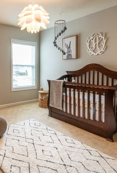 a baby's room with a crib, rug and pictures on the wall