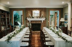 a long dining table set up with white linens and greenery on the tables