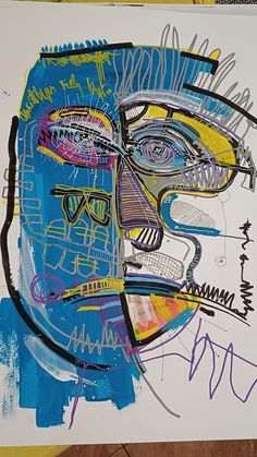 an abstract painting with blue, yellow and purple colors on it's face next to a piece of paper