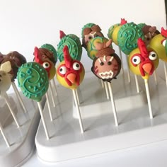 there are many cake pops decorated like angry birds and roosters on the sticks with green icing