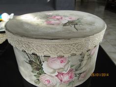 a white box with pink roses painted on it's sides and lace around the lid