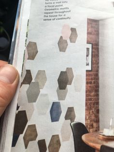 a person holding up a magazine with geometric tiles on it