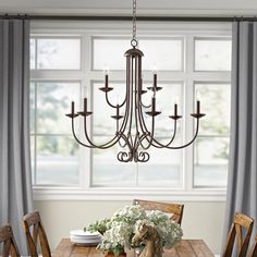 a chandelier hanging over a wooden dining room table with white flowers on it