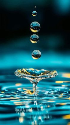 three drops of water are falling into the blue and yellow water with gold highlights on it