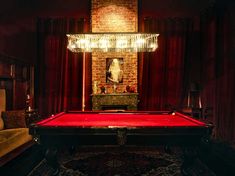 a pool table in a room with red curtains and a chandelier hanging from the ceiling