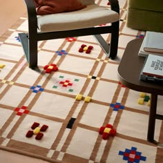 a chair and table in a room with a rug on the floor that looks like a game