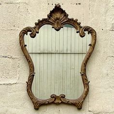 an ornate mirror mounted to the side of a white brick wall next to a window