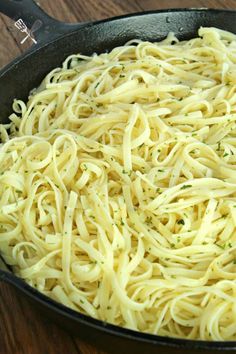 a skillet filled with pasta on top of a wooden table