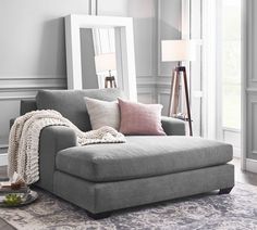 a living room with a gray couch and mirror