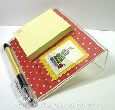 a note pad and pen sitting on top of a clear box with red polka dot paper