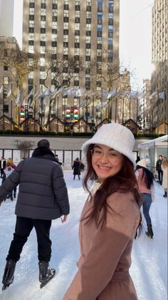 a woman standing in the middle of an ice skating rink with buildings in the background