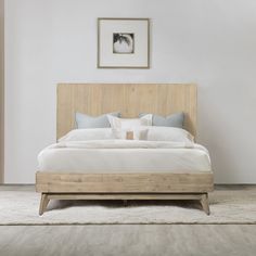 a large bed sitting in a bedroom next to a white wall and wooden headboard