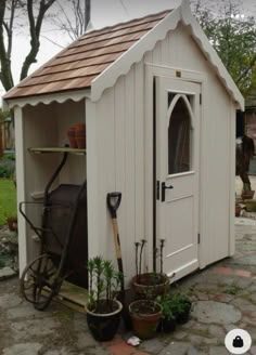 a garden shed with a bicycle and potted plants in the yard next to it