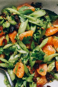 a salad with oranges, celery and other vegetables in a white bowl