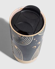 a close up of a cup with a lid on a white surface and an abstract pattern