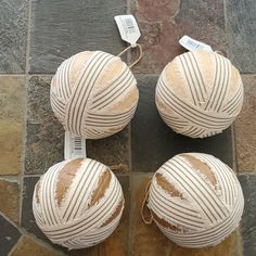 three balls of yarn sitting on top of a stone floor next to each other with tags attached